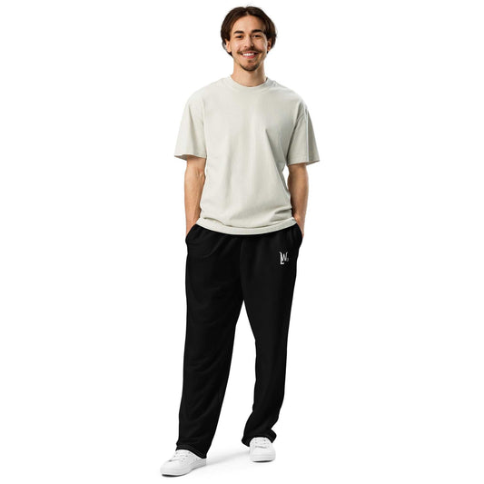 Man wearing black LegendWithin wide-leg joggers with elastic waistband and side pockets paired with a light grey t-shirt and white sneakers